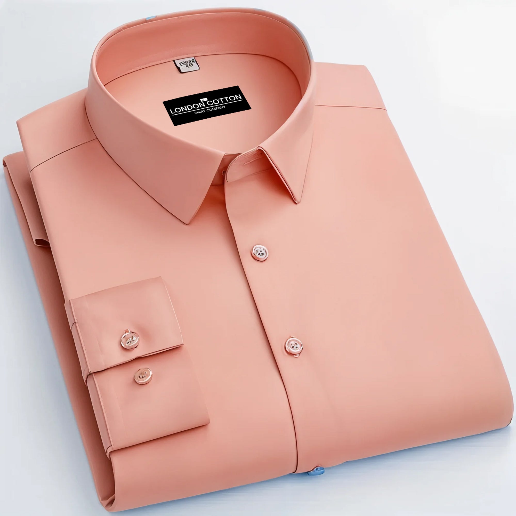 Folded peach-colored shirt with 'London Cotton' label on a light blue background