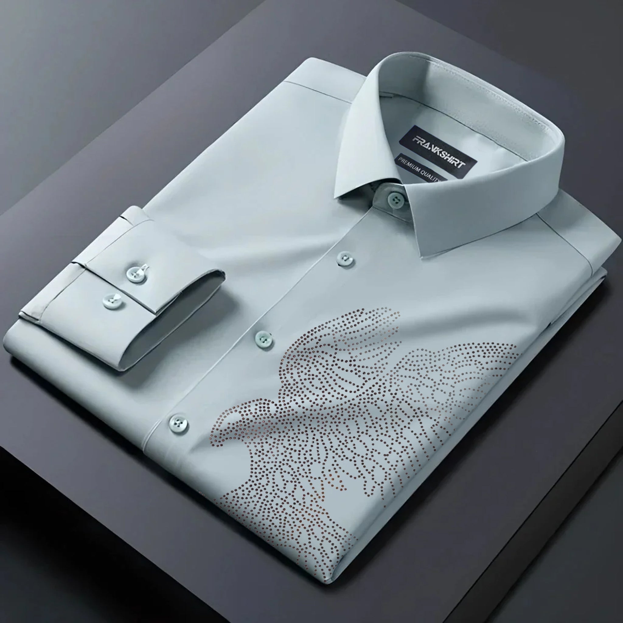 Folded light gray dress shirt with floral pattern on a dark surface