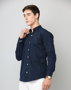 Man wearing a navy blue shirt with white buttons on a gray background