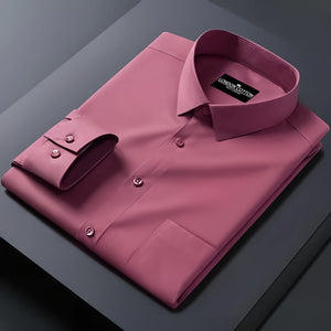 Folded pink dress shirt with a brand label on a dark surface
